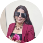 Emili tiene cabello largo y oscuro con tonos rojizos. Lleva puestas unas gafas de sol grandes y cuadradas de color oscuro que cubren buena parte de su rostro. Su expresión facial muestra una ligera sonrisa. Está vestida con un blazer o chaqueta formal de color fucsia o rosa intenso sobre lo que parece ser una prenda negra con escote. Alrededor de su cuello lleva un collar elaborado de múltiples hilos con cuentas de colores, posiblemente en tonos claros y oscuros. En sus manos, que son visibles en la parte inferior, sostiene unas flores rosas. Sus uñas se ven claras o pintadas.